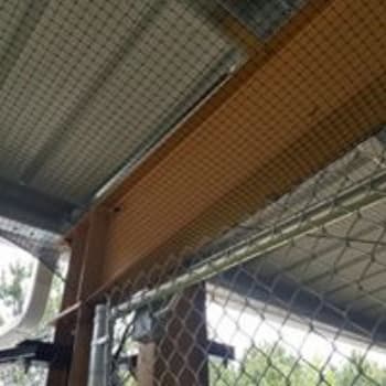 Bird netting is installed under an industrial building's roof